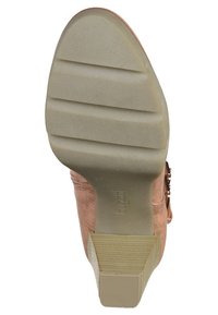 Suela de un zapato, con un material de goma texturizada de color marrón claro, con surcos horizontales y un ligero tacón. Nombre de la marca "bugatti" visible.