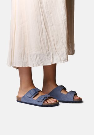 Sinised seemisnahast sandaalid kahe reguleeritava pandlaga, korkjalatsipõhja ja tekstuurse kummist tallaga. Kandmisega pikk, voolav kreemikas seelik.