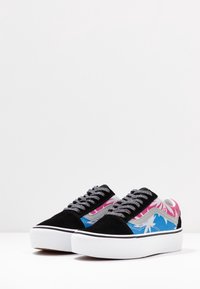 Baskets en daim noir avec des accents de motif tropical rose et bleu, des lacets gris, et une semelle extérieure en caoutchouc blanc. Design décontracté aux couleurs contrastées.