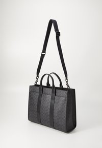 Black tote bag with a textured design, dual top handles, and adjustable shoulder strap. Features sleek finishes and minimalistic style.