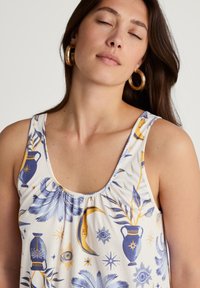 Top bianco senza maniche con motivi blu e gialli che raffigurano vasi, lune ed elementi celestiali. Tessuto morbido con un fit rilassato e scollatura arricciata.