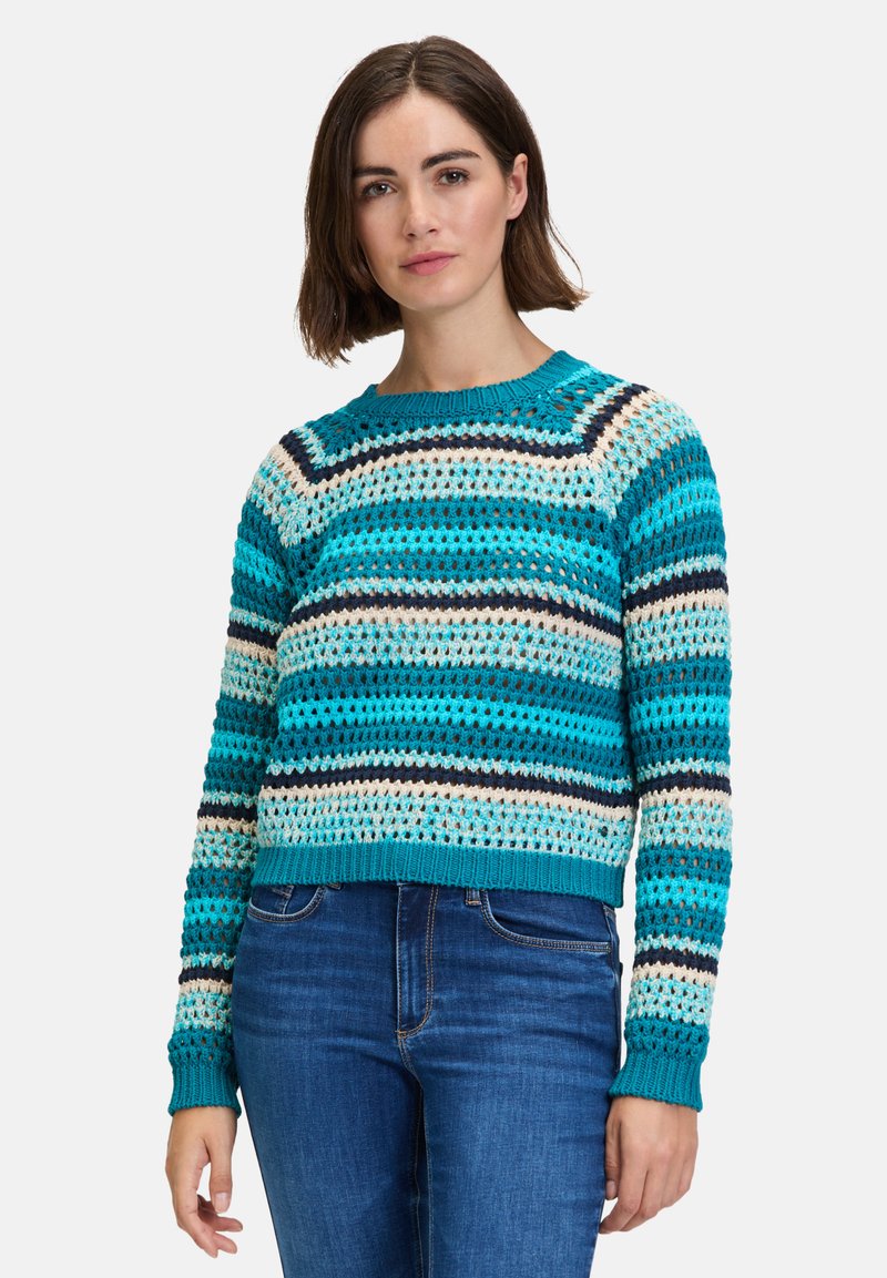 Pull en crochet avec des rayures horizontales turquoise, crème et marine. Encolure ronde et poignets côtelés avec une coupe courte.