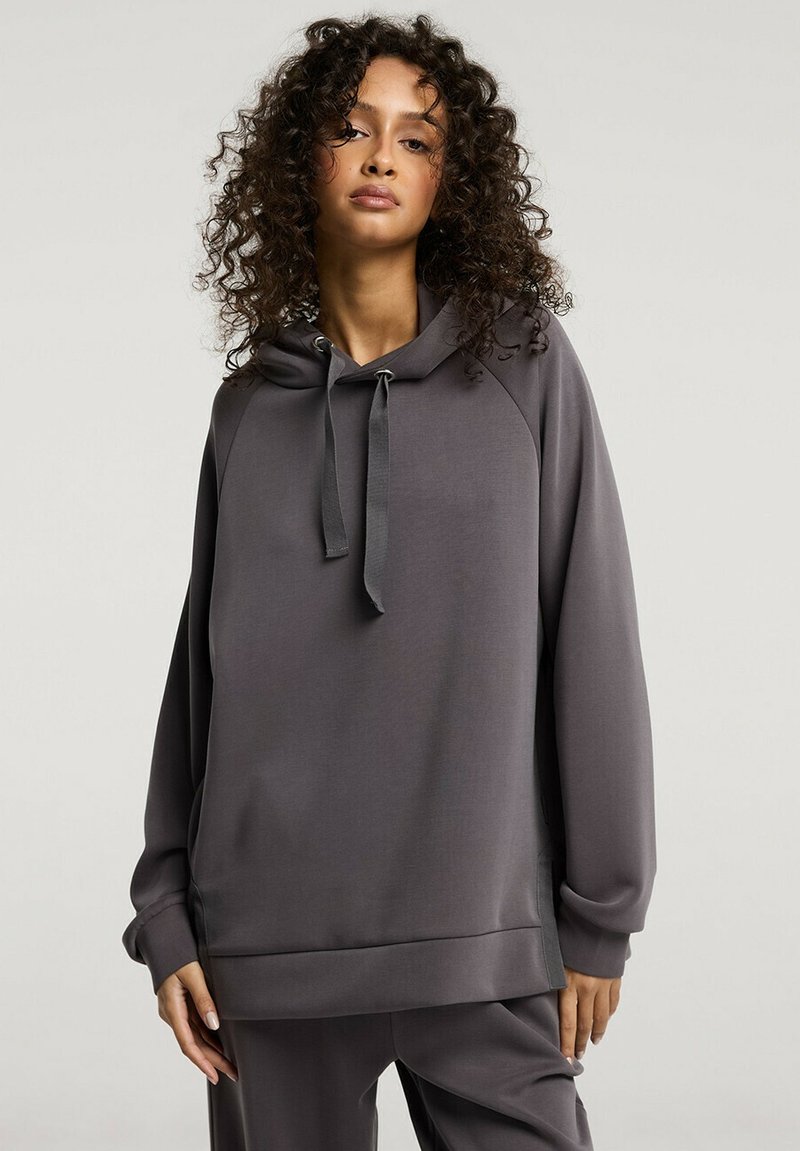 Szara bluza z kapturem wykonana z miękkiego materiału, o luźnym kroju. Posiada sznurki w kapturze, ściśnięte mankiety oraz gładką fakturę.