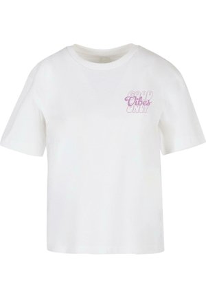Camiseta de manga corta blanca hecha de algodón, con texto rosa "SOLO BUENAS VIBRACIONES" en la parte izquierda del pecho. Diseño clásico de cuello redondo.
