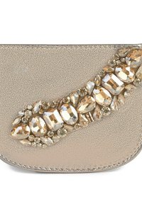 Bolso de mano beige con superficie texturizada, que presenta una embellishment curva de varias piedras preciosas transparentes y de color champán. Detalle de acabado en plata.