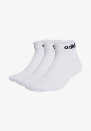 Tres pares de calcetines deportivos blancos con el logotipo negro de "adidas" en el puño, de grosor medio, altura de tobillo, textura suave y puntera reforzada.