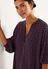 Paarse blouse met zwart bladpatroon, met een V-hals en gathered mouwen. Gemaakt van lichtgewicht stof met een ontspannen pasvorm.