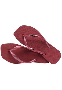 Căptușeli roșii din cauciuc, cu un suport texturat pentru picior, curele subțiri și un logo al mărcii pe lateral. Forma este plată și lată.