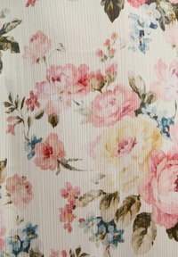 Tessuto con stampa floreale che presenta fiori rosa, gialli e blu su uno sfondo crema texturizzato con linee verticali sottili.