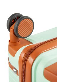 Hard-shell koffer met een mintgroene behuizing, oranje accenten en een gestructureerde rits. De spinwielen hebben een koolstofpatroon oppervlak.