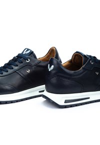 Marineblaue Ledersneaker mit weißen Akzenten, ausgestattet mit Schnürdesign, gepolstertem Kragen und kontrastierender weißer Sohle mit strukturiertem Griff.