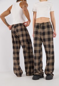 Geklede broek in bruin en zwart stof, wijdere pasvorm met een elastische tailleband en trekkoord, voorzien van een zijzak en een zachte textuur.