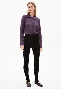 Paarse shirt met textuur en kraag, gecombineerd met zwarte leggings en zwarte ballerina's. De outfit heeft een minimalistisch ontwerp.