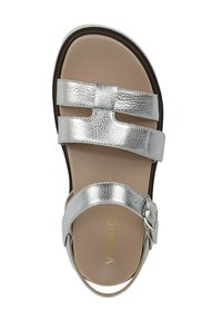 Sandal in pelle argento caratterizzato da tre cinturini stretti, chiusura con fibbia e un plantare beige chiaro con marchio in rilievo. Texture a grana orizzontale.