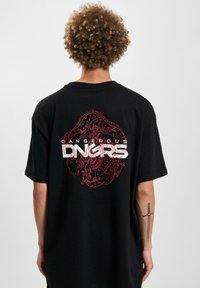 Svart oversized t-skjorte med et slående rødt grafisk design av en drage og teksten "DANGEROUS LNGRS" på baksiden.
