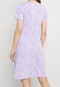Robe fleurie violette avec manches courtes et tissu doux. Le design comprend de petites fleurs blanches et une coupe décontractée avec une légère évasement.
