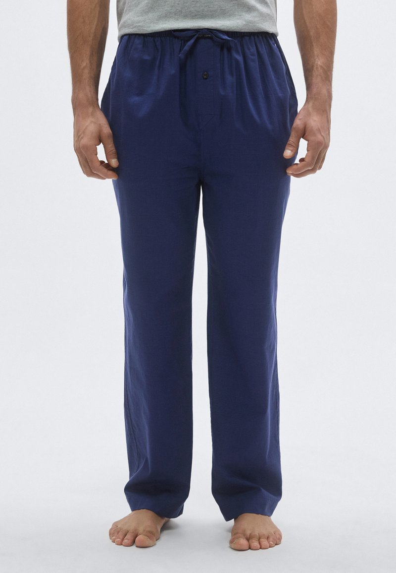 Granatowe, lekkie spodnie o luźnym kroju z elastycznym pasem i sznurkiem, z guzikiem oraz dwoma bocznymi kieszeniami.