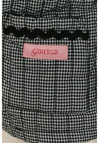 Černobílá kostkovaná tkanina s prošívanou texturou a vykrojeným černým okrajem. Obsahuje růžovou nálepku s nápisem "GIRLYtude" v písmu.