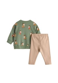 Zielona bluza z motywem wielu reniferów, zestawiona z prostymi beżowymi legginsami. Wykonana z miękkiego materiału z ściągaczami.
