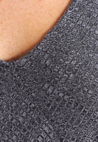 Szary teksturowany materiał z subtelnym wzorem, z dekoltem w serek i zbliżenie na splot oraz szycie tkaniny.