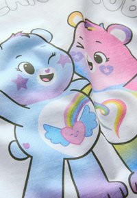 Weißes Baumwoll-T-Shirt mit kurzen Ärmeln, das niedliche cartoonhafte Bären in Blau und Pink zeigt, mit Herzen und Regenbögen auf ihren Bäuchen und bunten Akzenten.