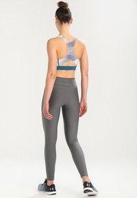 Szare legginsy sportowe w połączeniu z wzorzystym biustonoszem sportowym z turkusowym pasem, zaprojektowane z myślą o komforcie i elastyczności.