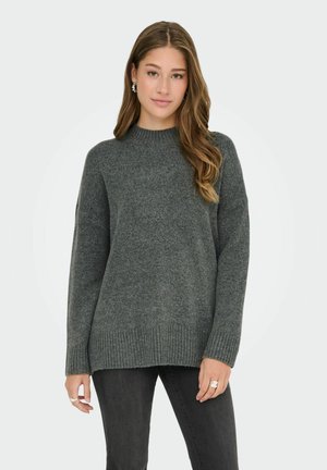 Pull en tricot gris avec un col montant, des poignets et un ourlet côtelés. Présente une coupe légèrement oversize et un tissu doux et texturé.