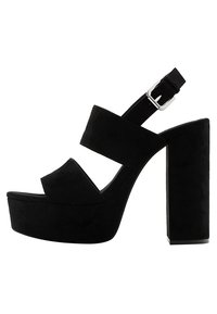 Black suede platform sandals with a thick block heel, double straps across the front, and an adjustable ankle strap with a silver buckle.
