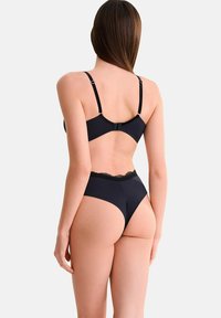 Ensemble de lingerie noire comprenant un soutien-gorge à finition lisse avec des bretelles ajustables, accompagné d'un slip taille haute avec bord en dentelle.