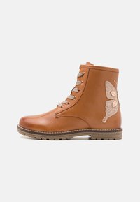 Bottine en cuir marron avec un design texturé en forme de papillon, œillets dorés et semelle en caoutchouc brun clair. Fermeture à lacets.