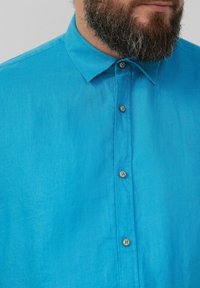 Turquoise linnen shirt met een kraag, voorzien van vijf bruine knopen langs de sluiting, met een gladde textuur en een lichtgewicht ontwerp.