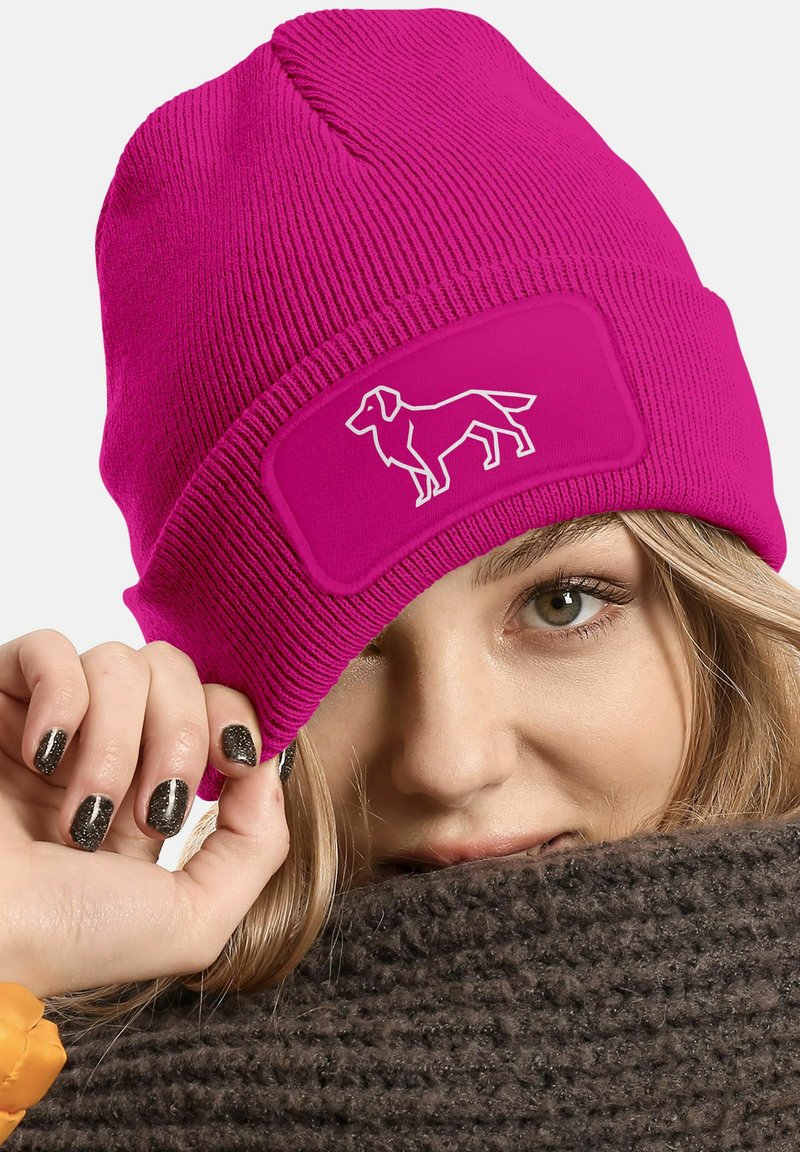 Magenta knit beanie with a ribbed design and a rectangular patch featuring a white dog silhouette. Soft texture and snug fit.