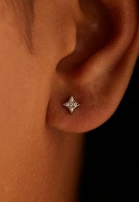 Boucle d'oreille en argent sterling en forme d'étoile avec une surface texturée, ornée de petits diamants incrustés pour scintiller. Gros plan de l'oreille.