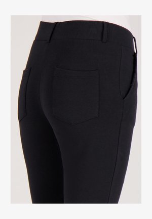 Zwarte stretchbroek met een gladde textuur, voorzien van een brede elastische tailleband en twee achterzakken. Eenvoudig, strak ontwerp zonder versieringen.