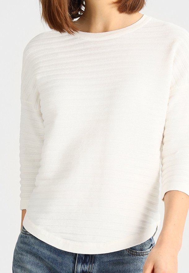 Haut blanc à manches longues avec des rayures horizontales en relief, un col rond et un ourlet légèrement courbé. Texture douce, coupe décontractée.