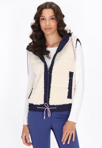 Gilet felpato crema con lati navy, zip completa, tasche, orlo con cordino e cappuccio. Il tessuto testurizzato contrasta con le sezioni lisce.