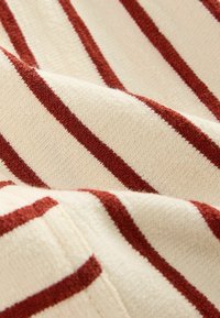Gebreide stof met een crèmekleurige achtergrond en dikke, horizontale kastanjebruine strepen. Zachte textuur met zichtbare stikdetails.