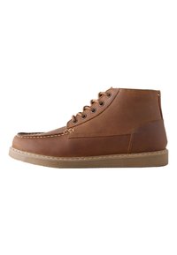 Bottes basses en cuir marron avec un bout arrondi, un design à lacets, des détails cousus et une semelle en caoutchouc. Présentent une surface lisse et texturée.