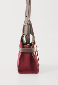Red suede handbag with brown leather accents, featuring a structured shape and a detachable shoulder strap, gold hardware, and a side detail.