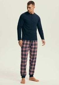 Granatowa koszula z długim rękawem i detalem z guzikami, zestawiona z czerwono-granatowymi, w kratę, piżamowymi spodniami z elastycznymi mankietami i sznurkiem w talii.