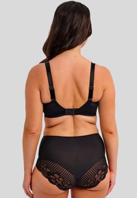 Musta pitsireunuksellinen rintaliivi ja siihen sopivat korkeavyötäröiset alushousut. Silkkinen kangas, jossa on läpinäkyvä pitsikuvio vyötäröllä ja takana.