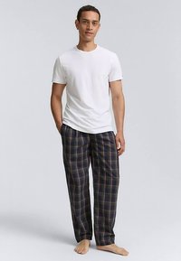 T-shirt en coton blanc associé à un pantalon en flanelle à carreaux bleu marine avec des accents verts, rouges et jaunes. Coupe ample avec une ceinture élastique.