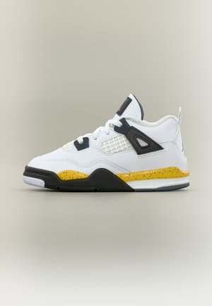 Baskets blanches avec des accents noirs et jaunes, détails noirs près des lacets, panneau en maille blanche et semelle mouchetée jaune et noire sur un fond neutre.