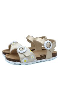 Sandales beiges avec des motifs de marguerites, des brides de cheville réglables et des boucles blanches. Semelles en liège et semelles en caoutchouc blanc texturé.