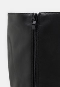 Borsa nera in ecopelle caratterizzata da una finitura liscia, una cerniera visibile sul lato e una forma strutturata senza ulteriori accenti o motivi.