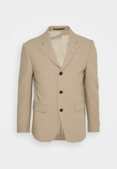 Blazer texturizado bege com lapelas recortadas, três botões, bolsos frontais e um design slim fit. Interior forrado com detalhes de costura subtis.