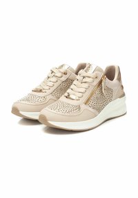 Zapatillas perforadas beige con un acento dorado brillante, diseño de cordones, cremallera lateral y suela de plataforma blanca. Detalle de cuero texturizado en toda la zapatilla.
