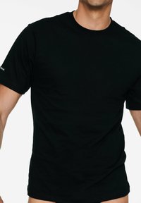 Czarna bawełniana koszulka z okrągłym dekoltem i krótkimi rękawami. Posiada małe logo na lewym rękawie. Gładka faktura, dopasowany krój.