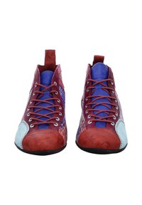 Un paio di sneakers alte e colorate con punte rosse, toppe laterali azzurre, lati intrecciati viola e lacci rossi su uno sfondo bianco.