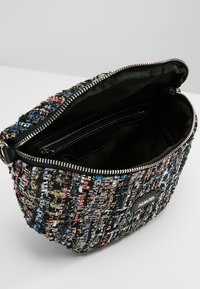 Borsa in tessuto multicolore e texture, con chiusura a zip e rivestimento nero. L'interno comprende una piccola tasca con zip per organizzare gli oggetti.